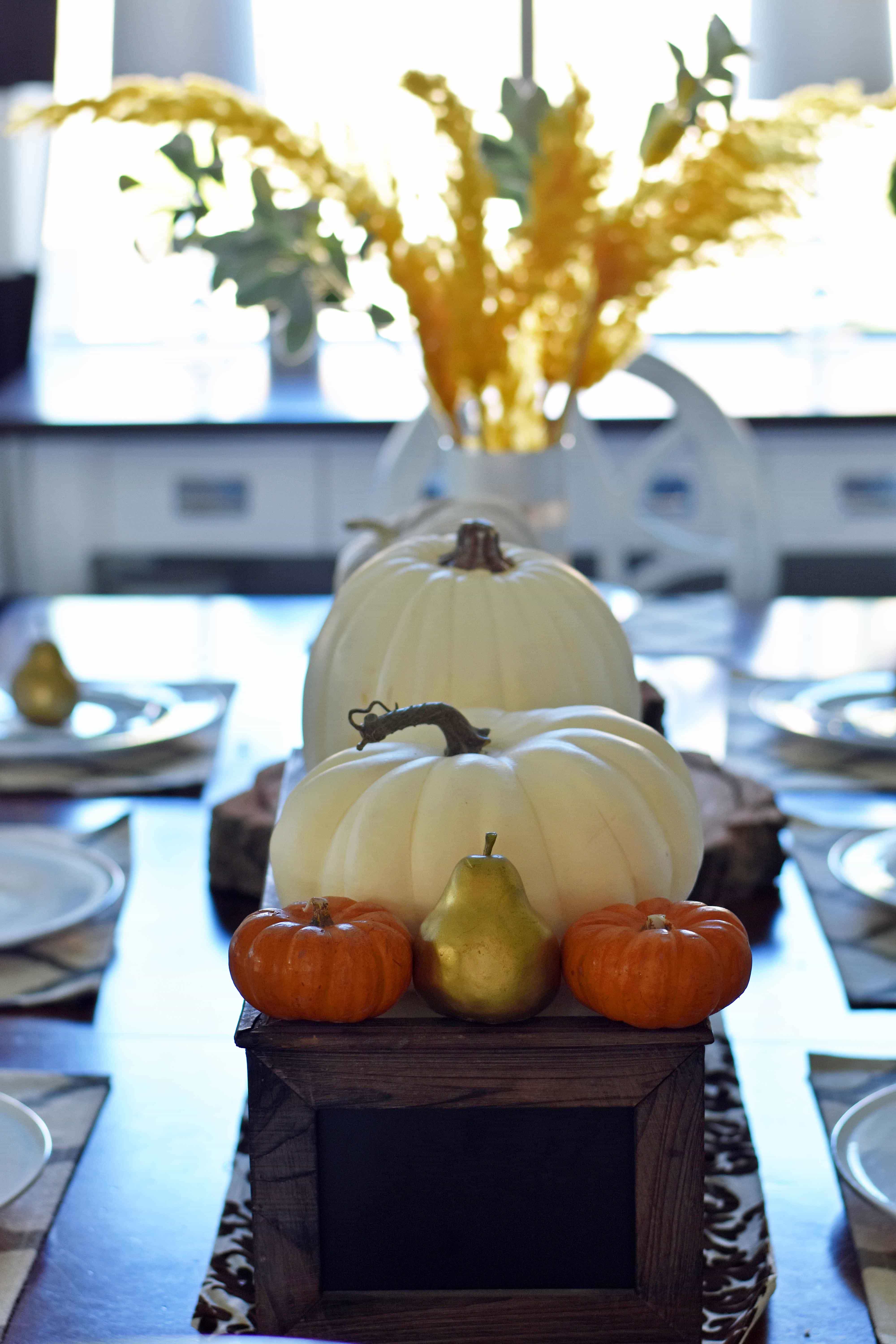 Fall Dining Room Table Decor Ideas. Craspedia Yellow Billy Ball Flowers in vintage vases. White pumpkins in wire baskets. Black and white striped pumpkin. Natural lamps, white entry table, and fall decor. Fixer Upper cotton ball stems. How to decorate your home for Fall.