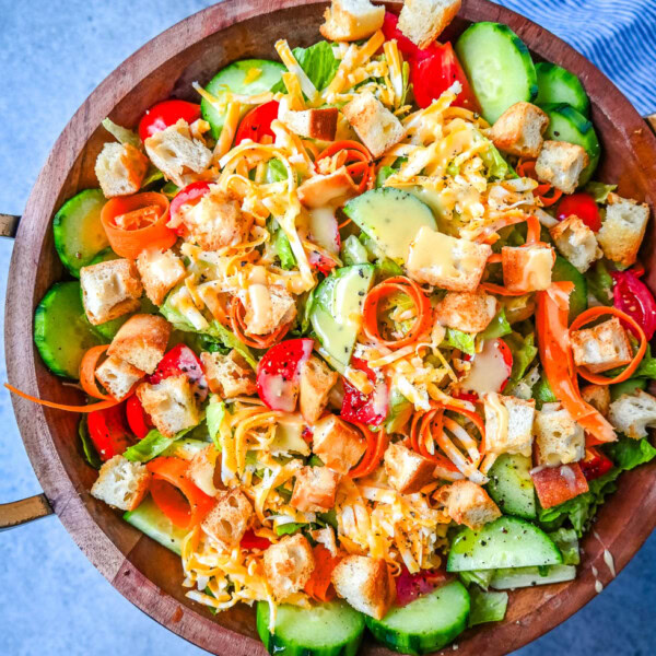 This fresh garden salad recipe is made with crisp lettuce, tomatoes, carrot ribbons, cucumbers, cheddar and mozzarella cheeses, homemade croutons, all tossed with a honey mustard or ranch dressing.
