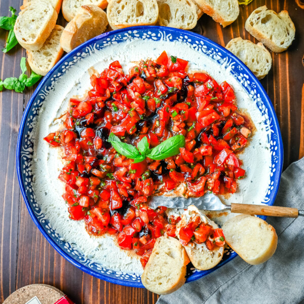 This quick and easy appetizer is made with garlic and herb Boursin cheese and topped with a fresh caprese salad made with tomatoes, olive oil, balsamic glaze, basil, and garlic. This Caprese Dip with boursin cheese pairs perfectly with crostinis or crackers.