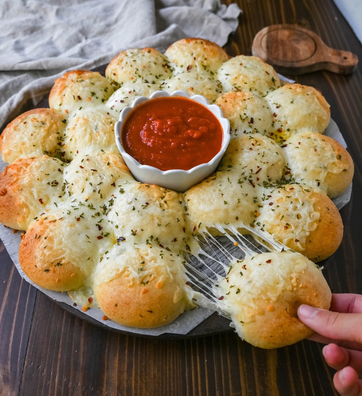 Cheesy garlic monkey bread, or garlic cheese pull-apart bread, made with Rhodes frozen dinner rolls, is soft, buttery, and cheesy. Each roll is dipped in garlic butter and then topped with gooey, melted mozzarella cheese that bubbles as it bakes. The result is a pull-apart bread that's golden on the outside, fluffy on the inside, and has cheesy, garlicky goodness in every bite. 