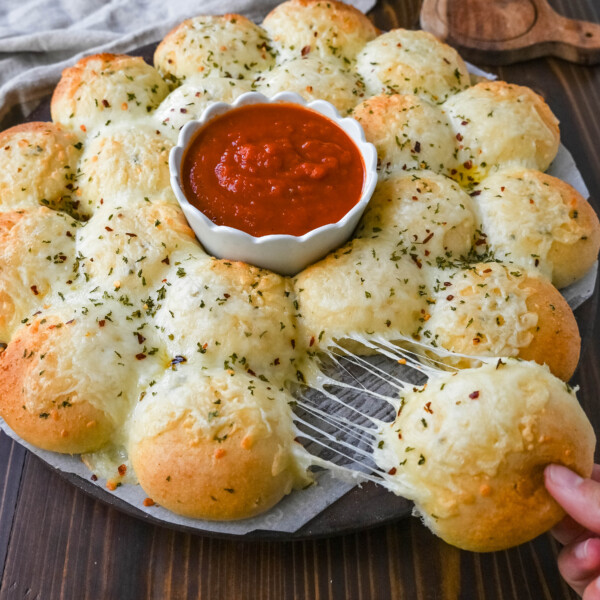 Cheesy garlic monkey bread, or garlic cheese pull-apart bread, made with Rhodes frozen dinner rolls, is soft, buttery, and cheesy. Each roll is dipped in garlic butter and then topped with gooey, melted mozzarella cheese that bubbles as it bakes. The result is a pull-apart bread that's golden on the outside, fluffy on the inside, and has cheesy, garlicky goodness in every bite.