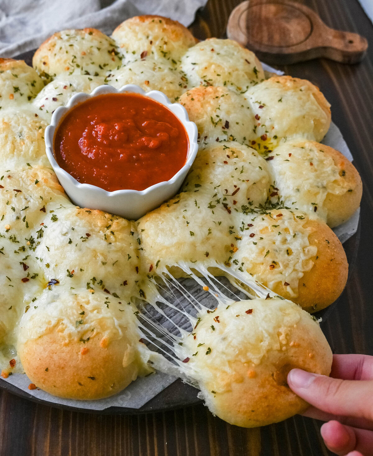 Cheesy garlic monkey bread, or garlic cheese pull-apart bread, made with Rhodes frozen dinner rolls, is soft, buttery, and cheesy. Each roll is dipped in garlic butter and then topped with gooey, melted mozzarella cheese that bubbles as it bakes. The result is a pull-apart bread that's golden on the outside, fluffy on the inside, and has cheesy, garlicky goodness in every bite.