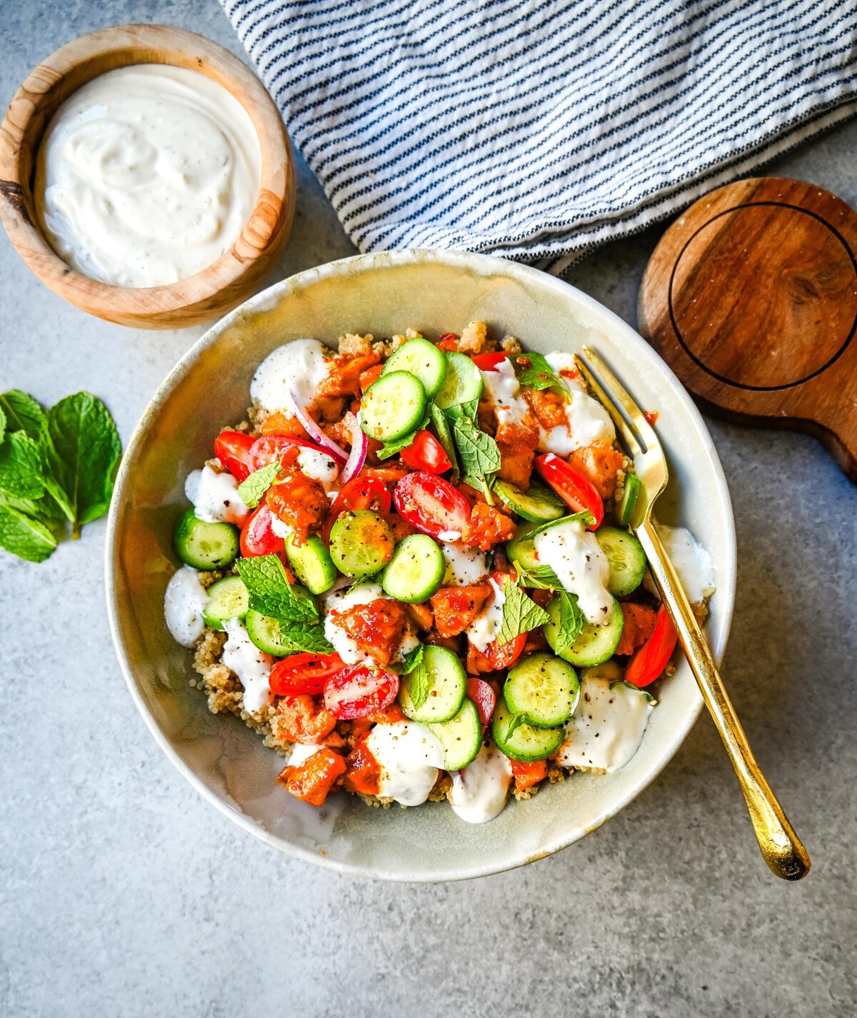 Mediterranean Chicken Bowls are made with sweet and spicy harissa honey chicken, fluffy quinoa, a Greek salad, and creamy tzatziki sauce. It is a spicy, sweet, crunchy, and creamy, healthy chicken bowl.