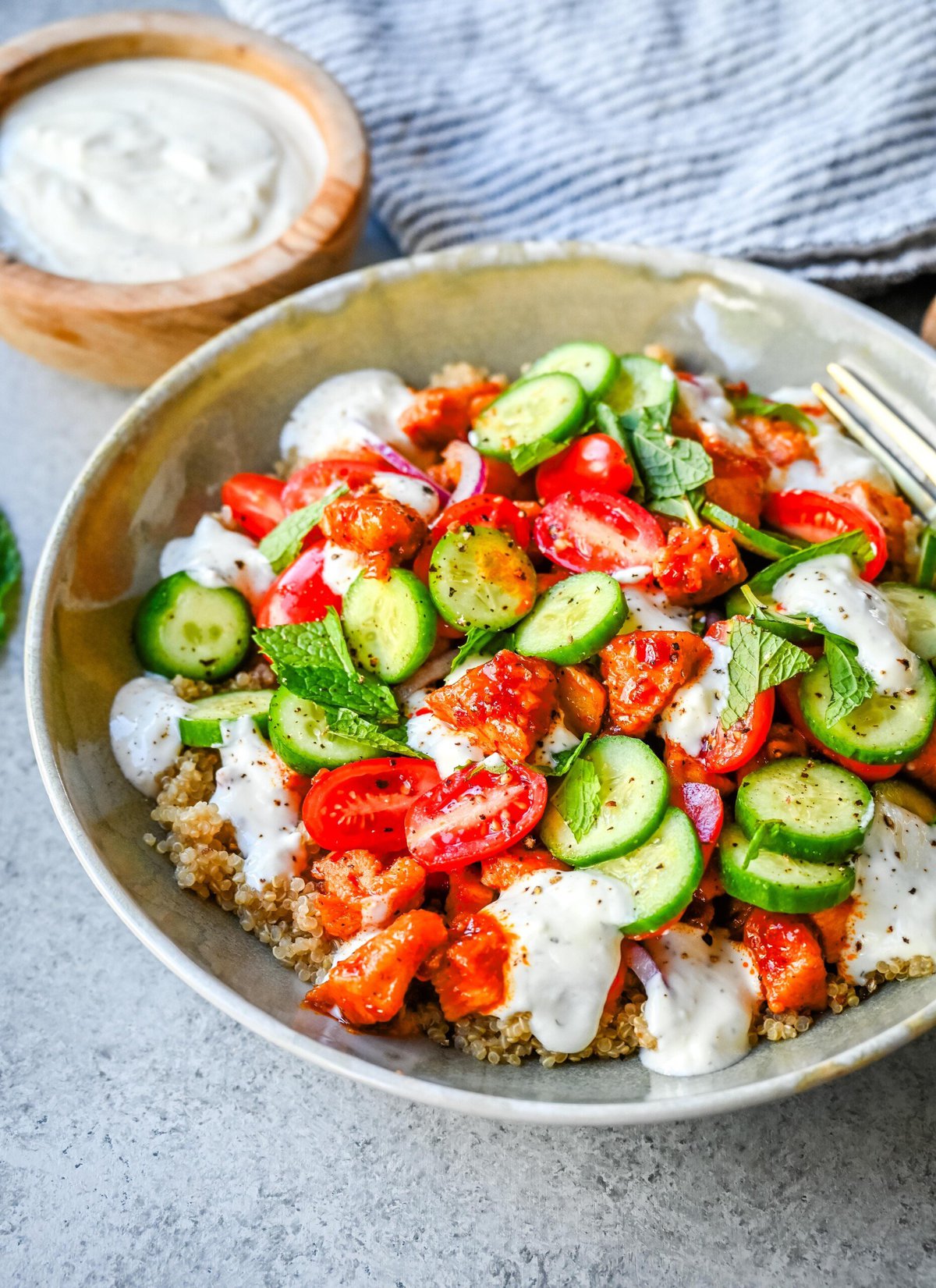 Mediterranean Chicken Bowls are made with sweet and spicy harissa honey chicken, fluffy quinoa, a Greek salad, and creamy tzatziki sauce. It is a spicy, sweet, crunchy, and creamy, healthy chicken bowl.