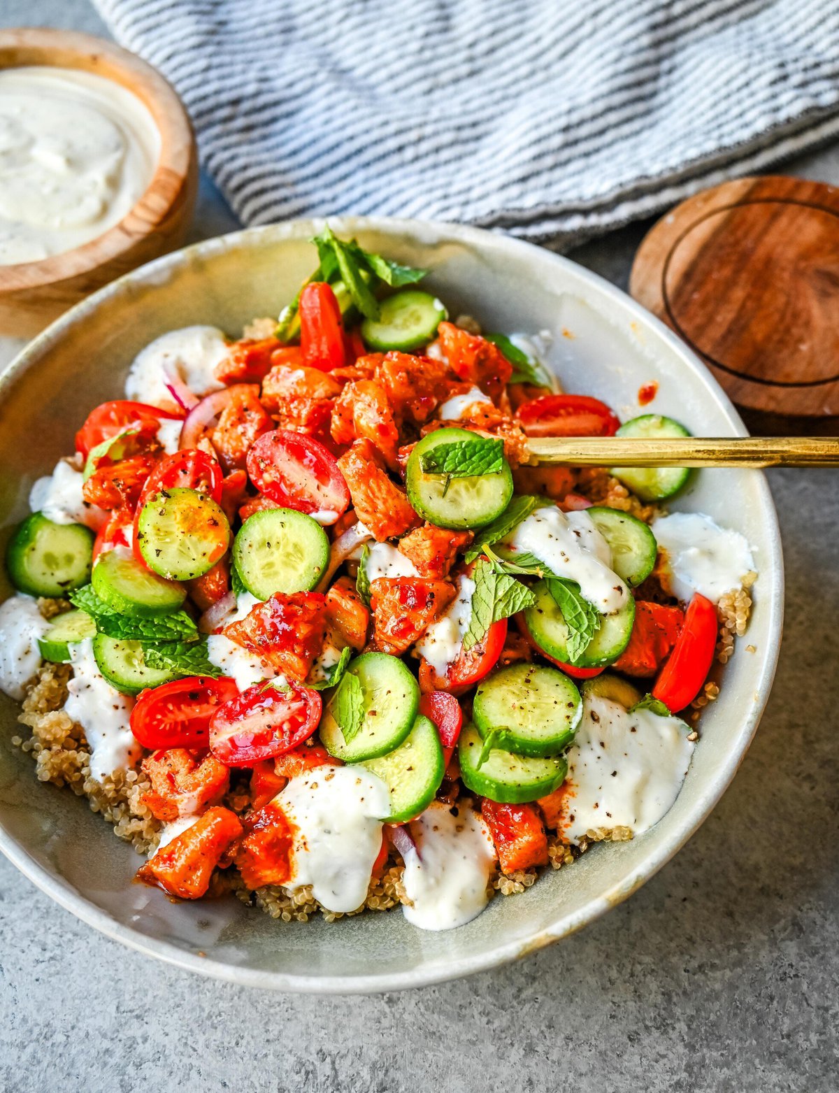 Mediterranean Chicken Bowls are made with sweet and spicy harissa honey chicken, fluffy quinoa, a Greek salad, and creamy tzatziki sauce. It is a spicy, sweet, crunchy, and creamy, healthy chicken bowl.