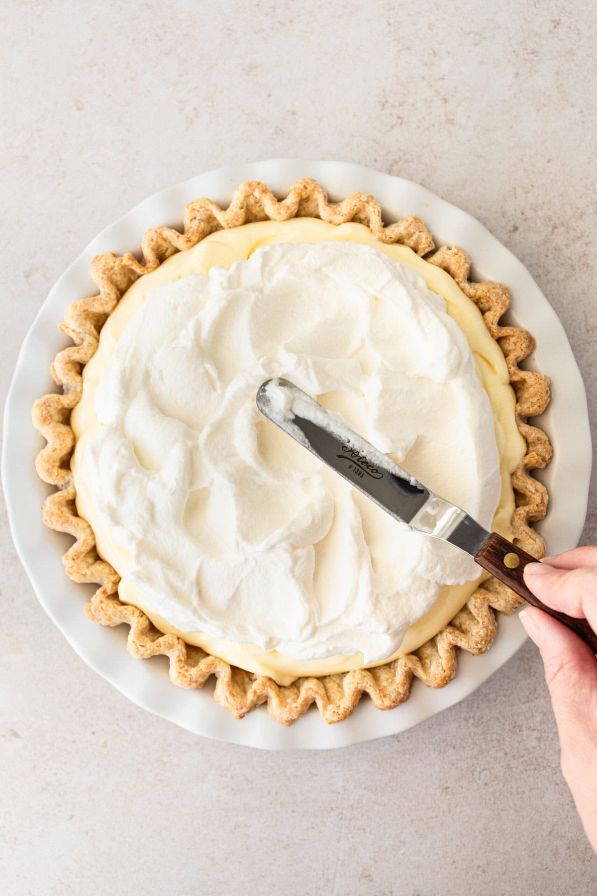 Spread fresh whipped cream on top of banana cream pie.