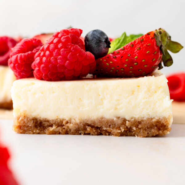 Creamy luscious cheesecake bars with a buttery graham cracker crust and topped with fresh berries is a crowd-pleasing popular dessert! They feature a creamy, tangy cheesecake filling atop a buttery graham cracker crust, baked to perfection in a bar form. Whether you're looking for a treat for a party, a family dessert, or simply craving cheesecake, these cheesecake bars are a hit.