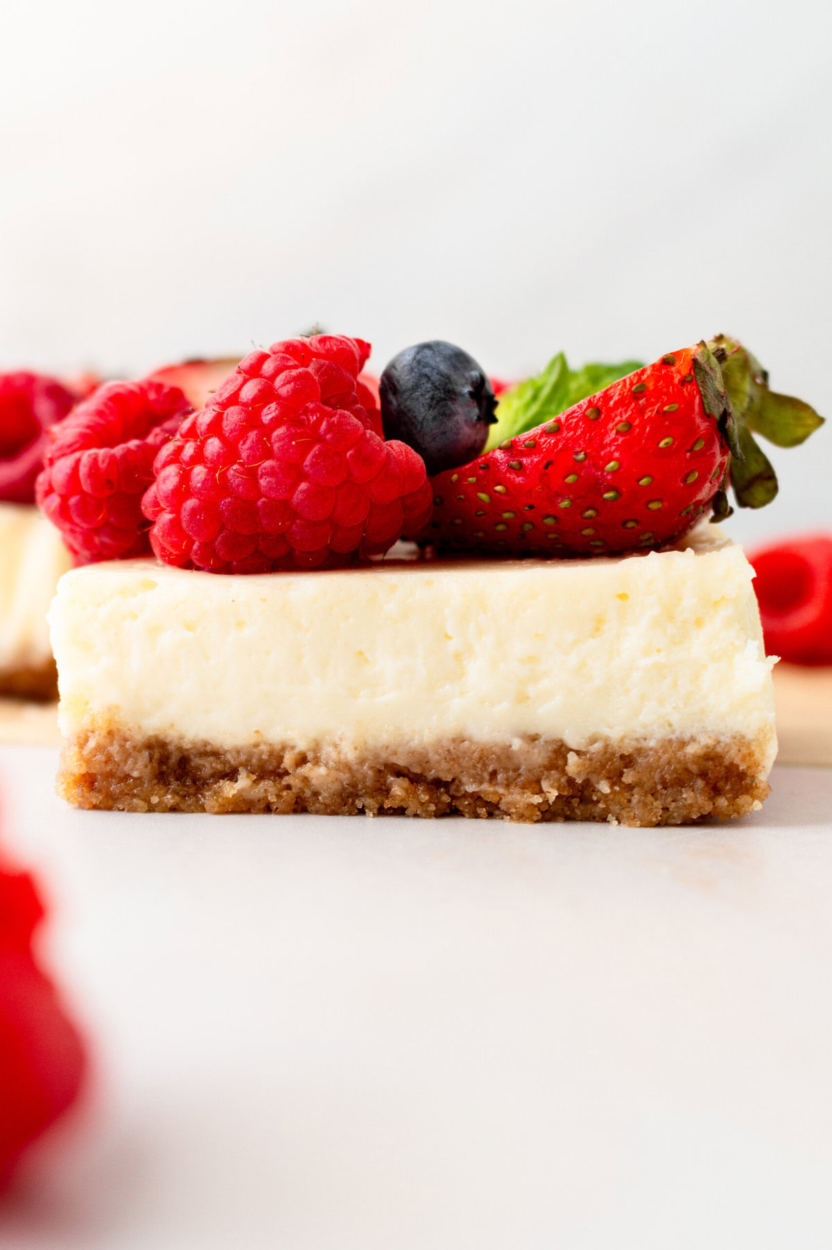 Creamy luscious cheesecake bars with a buttery graham cracker crust and topped with fresh berries is a crowd-pleasing popular dessert! They feature a creamy, tangy cheesecake filling atop a buttery graham cracker crust, baked to perfection in a bar form. Whether you're looking for a treat for a party, a family dessert, or simply craving cheesecake, these cheesecake bars are a hit.