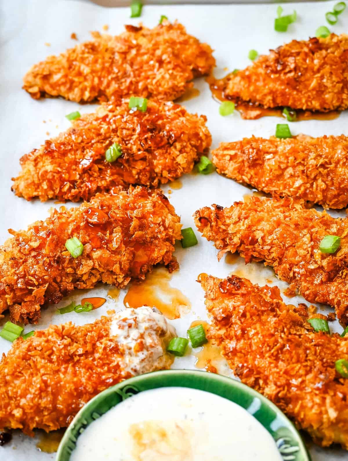 Tender, juicy chicken coated in a crispy cornflake crust that is baked to golden perfection, and then drizzled with sweet and spicy hot honey. These Crispy Crunchy Hot Honey Chicken Tenders deliver the perfect balance of crunch and heat, with a mouthwatering sticky glaze that keeps you coming back for more. 