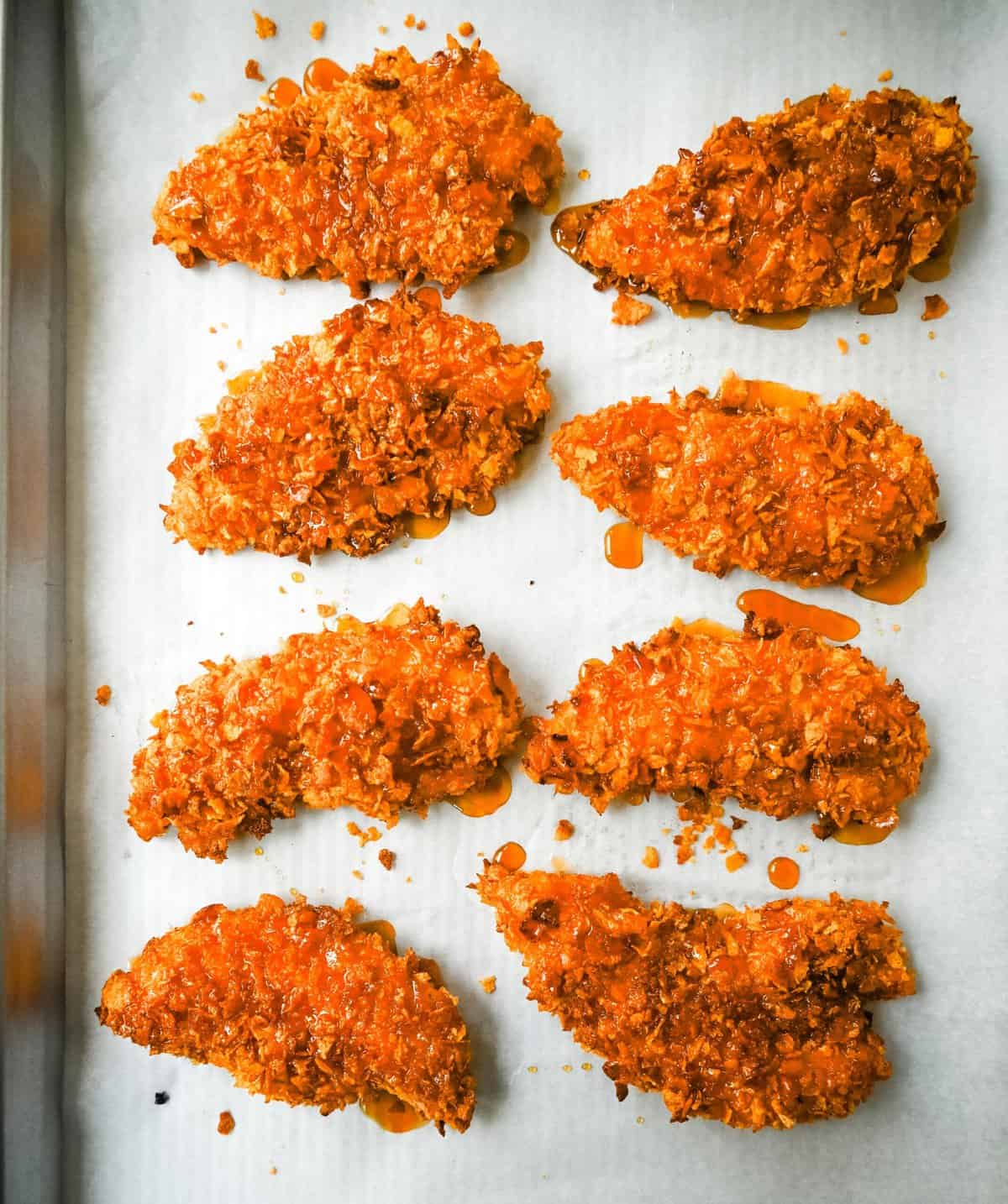 Tender, juicy chicken coated in a crispy cornflake crust that is baked to golden perfection, and then drizzled with sweet and spicy hot honey. These Crispy Crunchy Hot Honey Chicken Tenders deliver the perfect balance of crunch and heat, with a mouthwatering sticky glaze that keeps you coming back for more. 