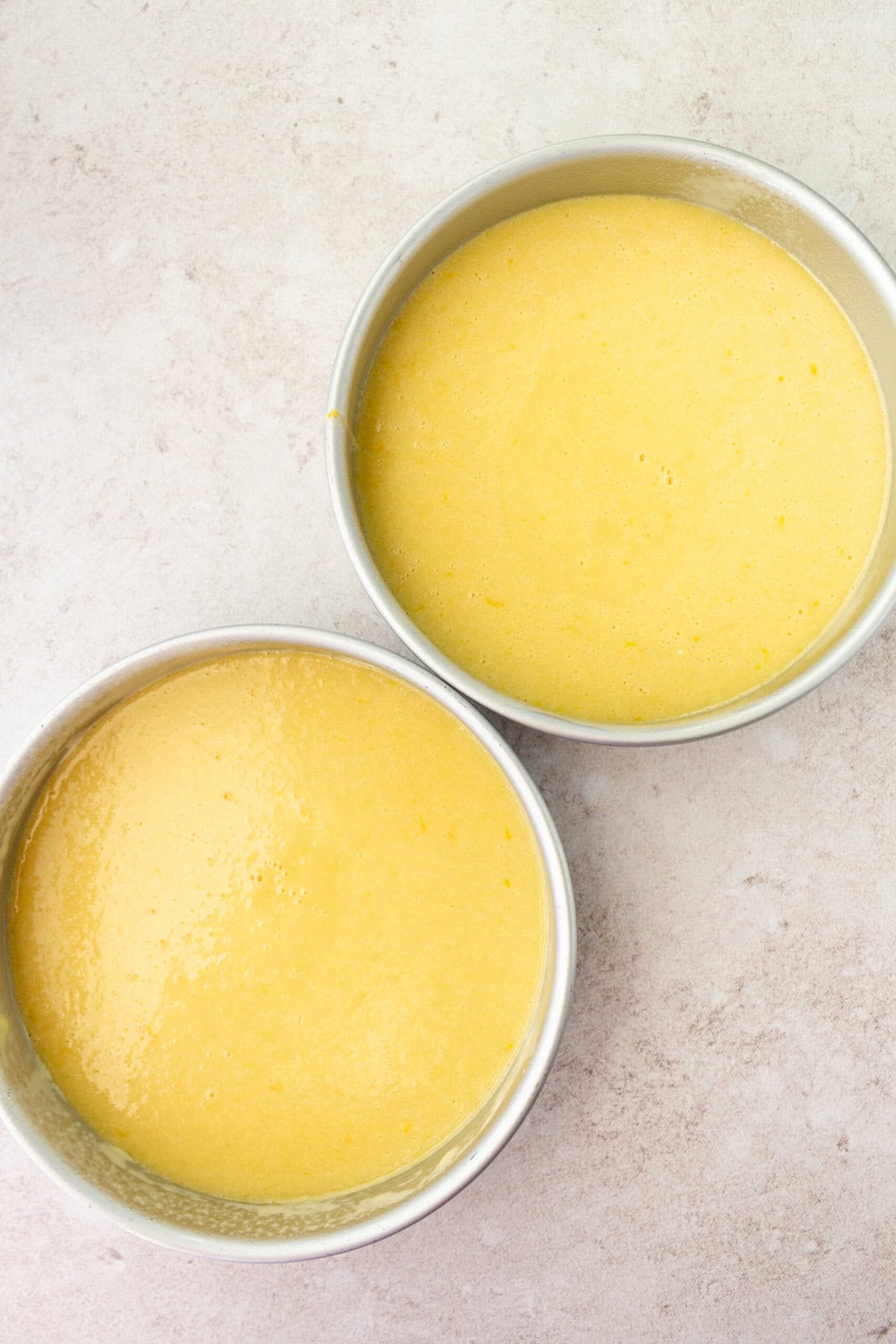 Lemon Olive Oil Cake batter poured into two 9-inch cake pans before baking