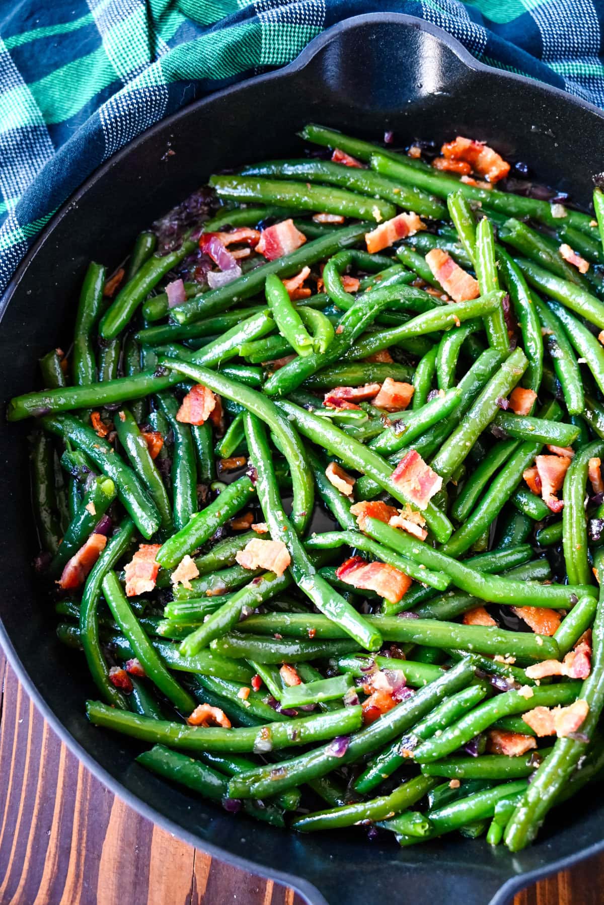 Bacon green beans in cast iron skillet. This recipe for brown sugar bacon green beans brings a sweet and savory twist to traditional green beans with the addition of crispy bacon, caramelized onions, and a buttery brown sugar glaze. This easy side dish is perfect for holiday dinners, Thanksgiving or as crowd pleasing side dish, adding just the right amount of richness to fresh green beans while keeping them fresh and crisp-tender. 