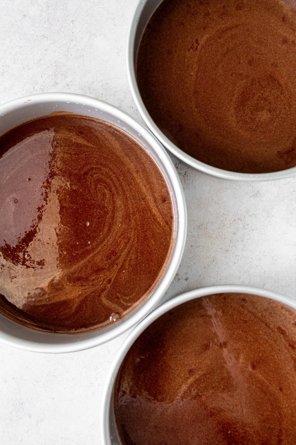 Homemade chocolate cake batter in cake pans ready to bake.