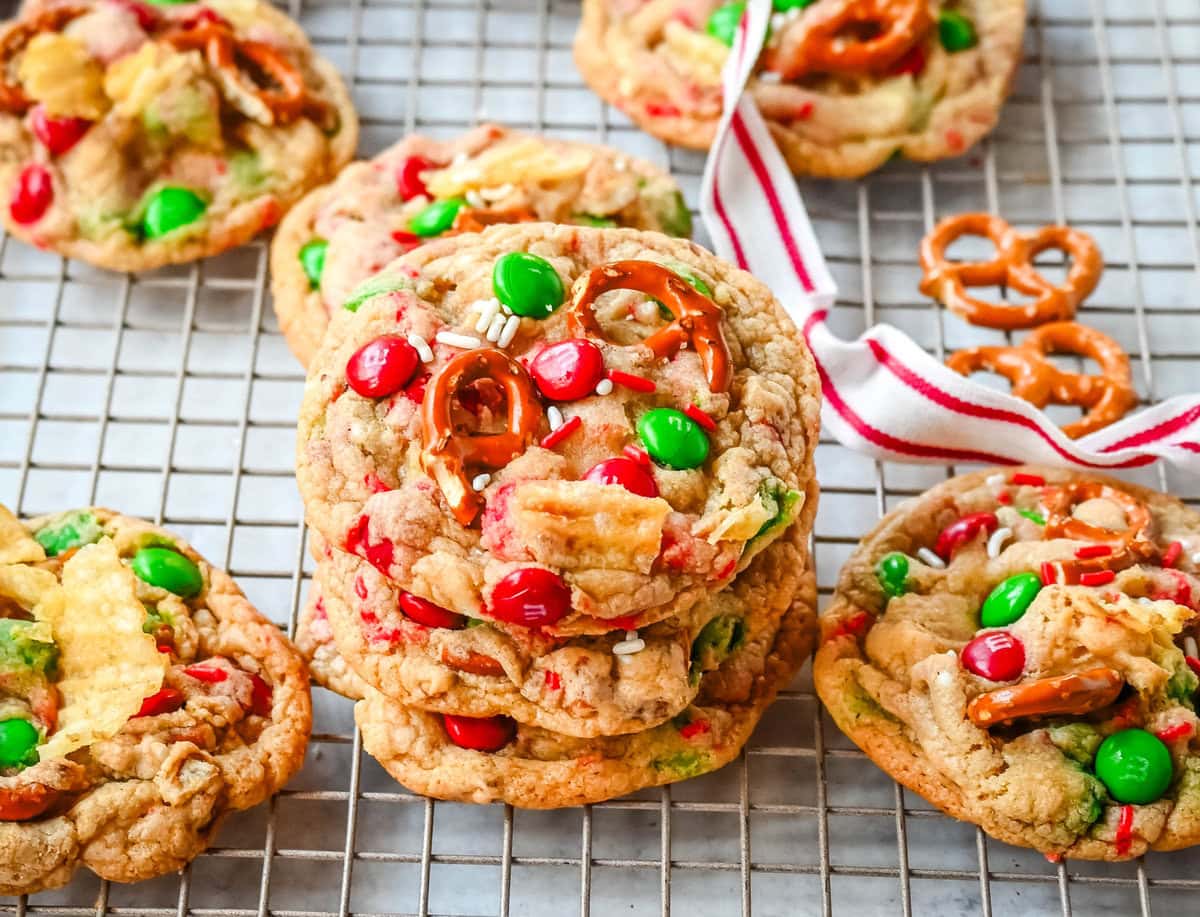 Stacked Christmas kitchen sink cookies. Get ready to bake the ultimate Christmas treat with these Christmas Kitchen Sink Cookies! Packed with holiday M&M's, pretzels, potato chips, sprinkles, and optional chocolate chips, these cookies bring together sweet, salty, and festive flavors in every bite. They're easy to make, fun to customize, and perfect for gifting, cookie swaps, and for your Christmas baking.