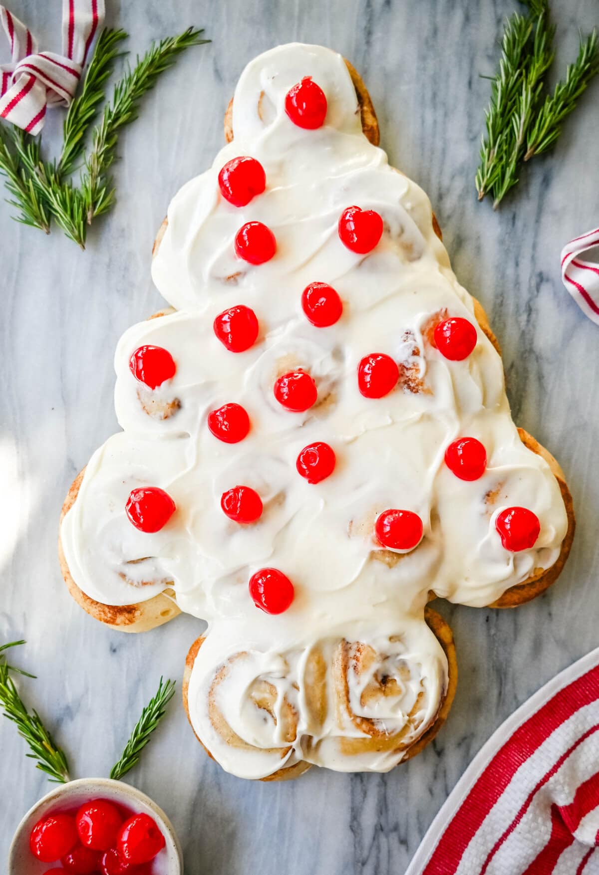 Are you looking for a sweet, festive, and delicious Christmas breakfast recipe for your Christmas morning? This Cinnamon Roll Christmas Tree is made with either homemade cinnamon roll dough or store-bought options like Rhodes frozen cinnamon rolls and covered in a creamy frosting. It can even be decorated with "red ornaments" -- maraschino cherries.