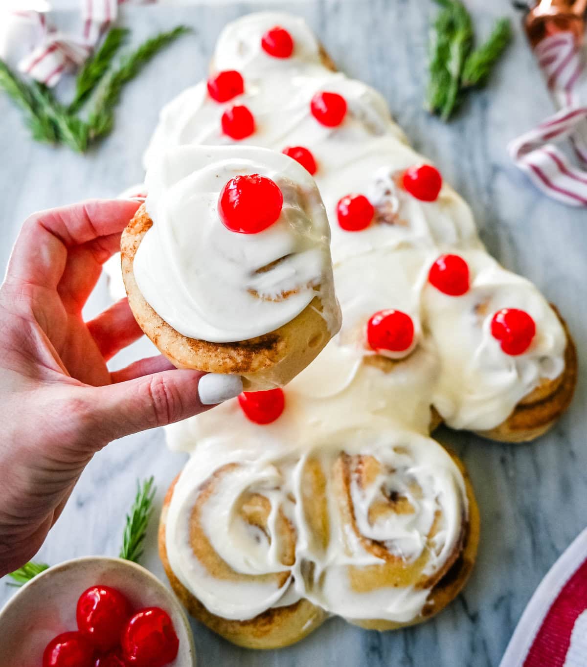 Are you looking for a sweet, festive, and delicious Christmas breakfast recipe for your Christmas morning? This Cinnamon Roll Christmas Tree is made with either homemade cinnamon roll dough or store-bought options like Rhodes frozen cinnamon rolls and covered in a creamy frosting. It can even be decorated with "red ornaments" -- maraschino cherries.