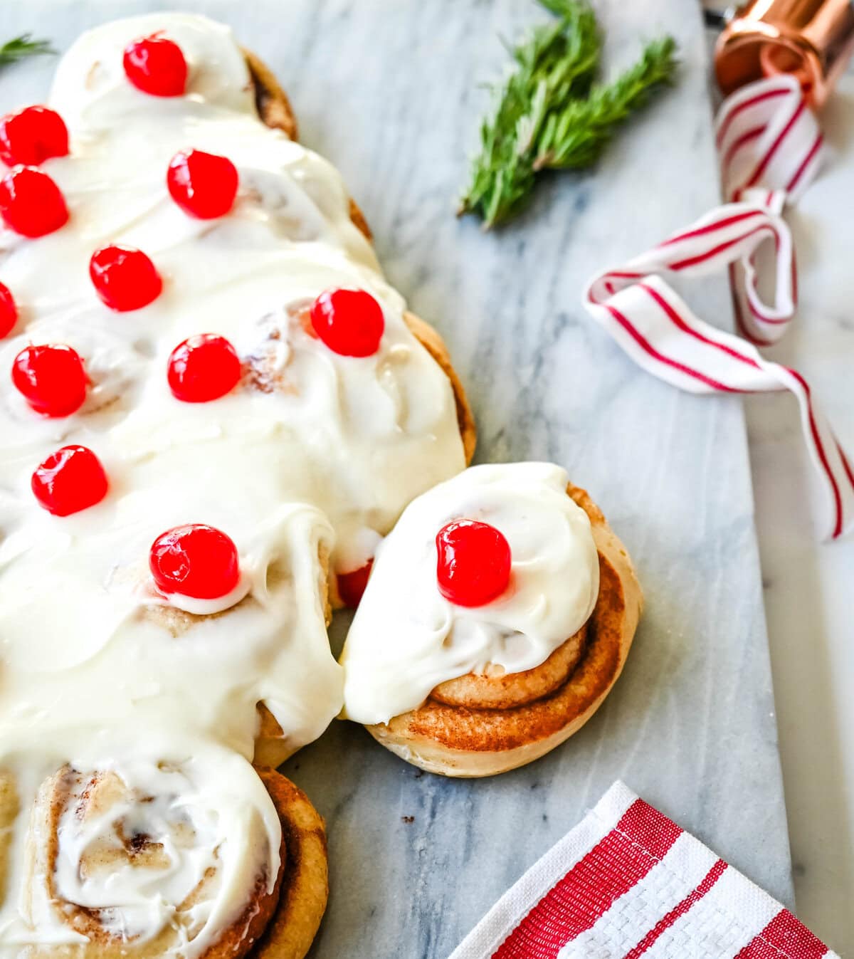 Are you looking for a sweet, festive, and delicious Christmas breakfast recipe for your Christmas morning? This Cinnamon Roll Christmas Tree is made with either homemade cinnamon roll dough or store-bought options like Rhodes frozen cinnamon rolls and covered in a creamy frosting. It can even be decorated with "red ornaments" -- maraschino cherries.