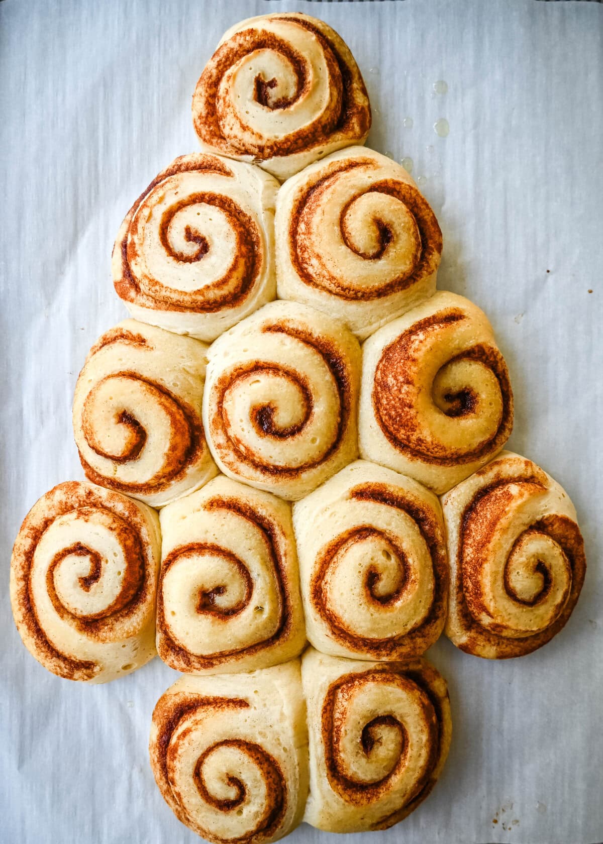 Bake the cinnamon rolls in a Christmas tree shape to make a Cinnamon Roll Christmas Tree