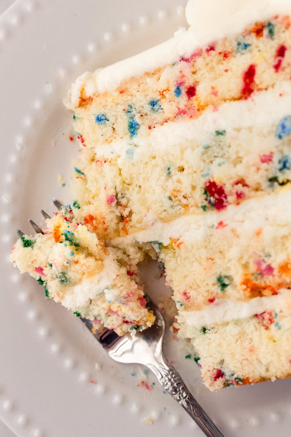 A fluffy homemade Funfetti birthday cake with rainbow sprinkles topped with a light cream cheese buttercream frosting and an array of sprinkles. This Confetti Cake recipe is the perfect birthday cake!