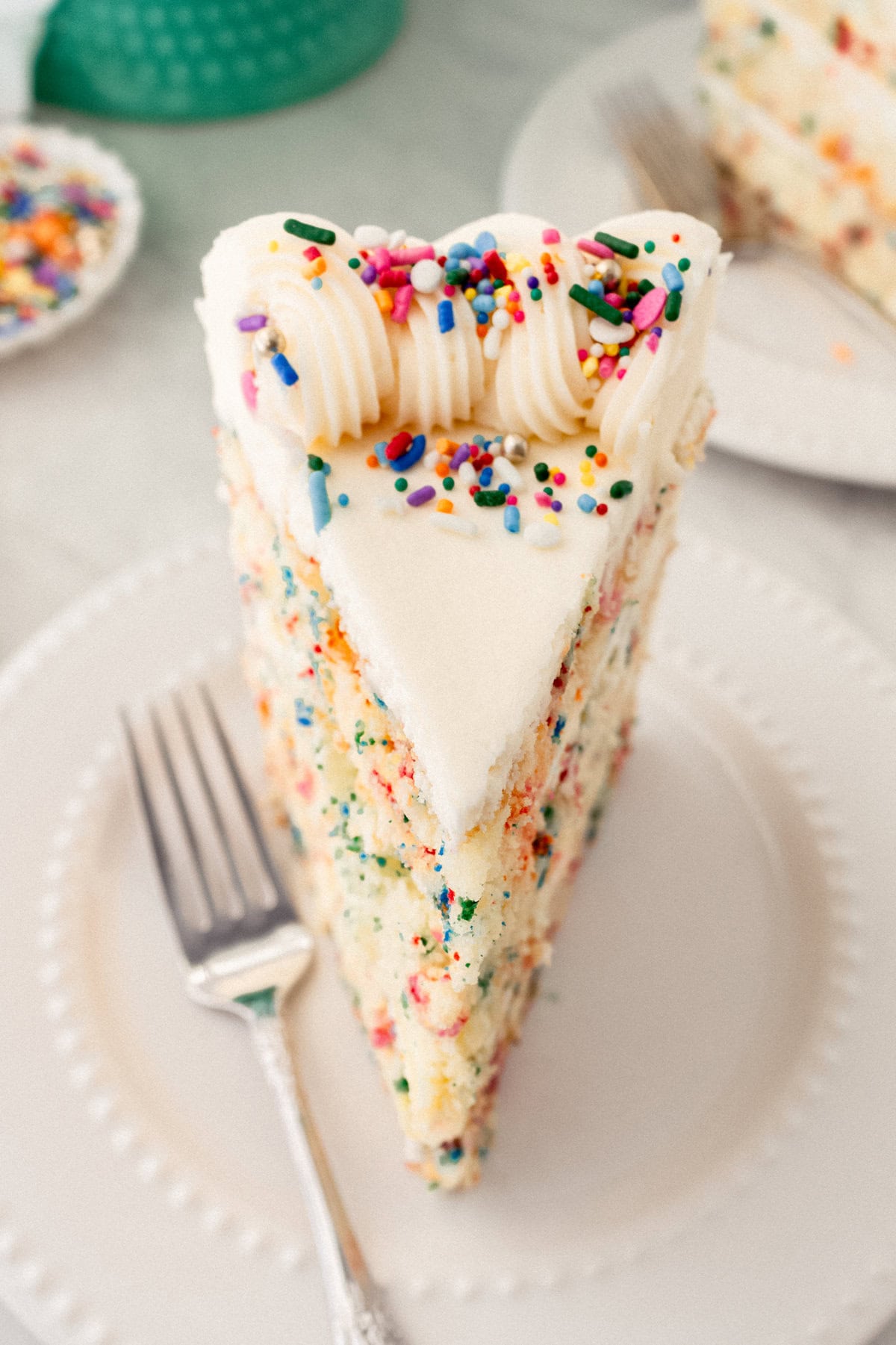 A fluffy homemade Funfetti birthday cake with rainbow sprinkles topped with a light cream cheese buttercream frosting and an array of sprinkles. This Confetti Cake recipe is the perfect birthday cake!