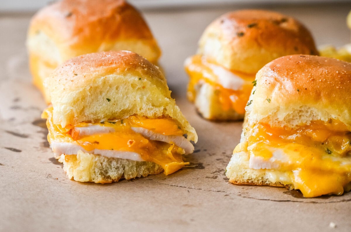 Garlic Herb Turkey and Cheddar Sliders. These Baked Turkey and Cheddar Sliders on Hawaiian Rolls with a sweet honey mustard spread and homemade garlic butter brushed on top are the perfect turkey slider recipe.  