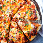 This Homemade BBQ Chicken Pizza is made with a Homemade Pizza Crust, BBQ Ranch Sauce, Mozzarella and Cheddar Cheeses, Red Onion, and a touch of Cilantro.  THE BEST BBQ CHICKEN PIZZA RECIPE.