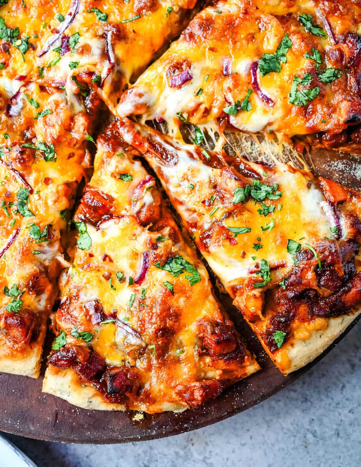 This Homemade BBQ Chicken Pizza is made with a Homemade Pizza Crust, BBQ Ranch Sauce, Mozzarella and Cheddar Cheeses, Red Onion, and a touch of Cilantro.  THE BEST BBQ CHICKEN PIZZA RECIPE.