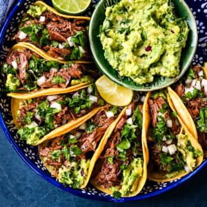 Tender, juicy, flavorful shredded beef with corn tortillas, fresh homemade guacamole, and a touch of cilantro and onion. These Slow Cooker Beef Tacos are so easy to make and everyone loves them!