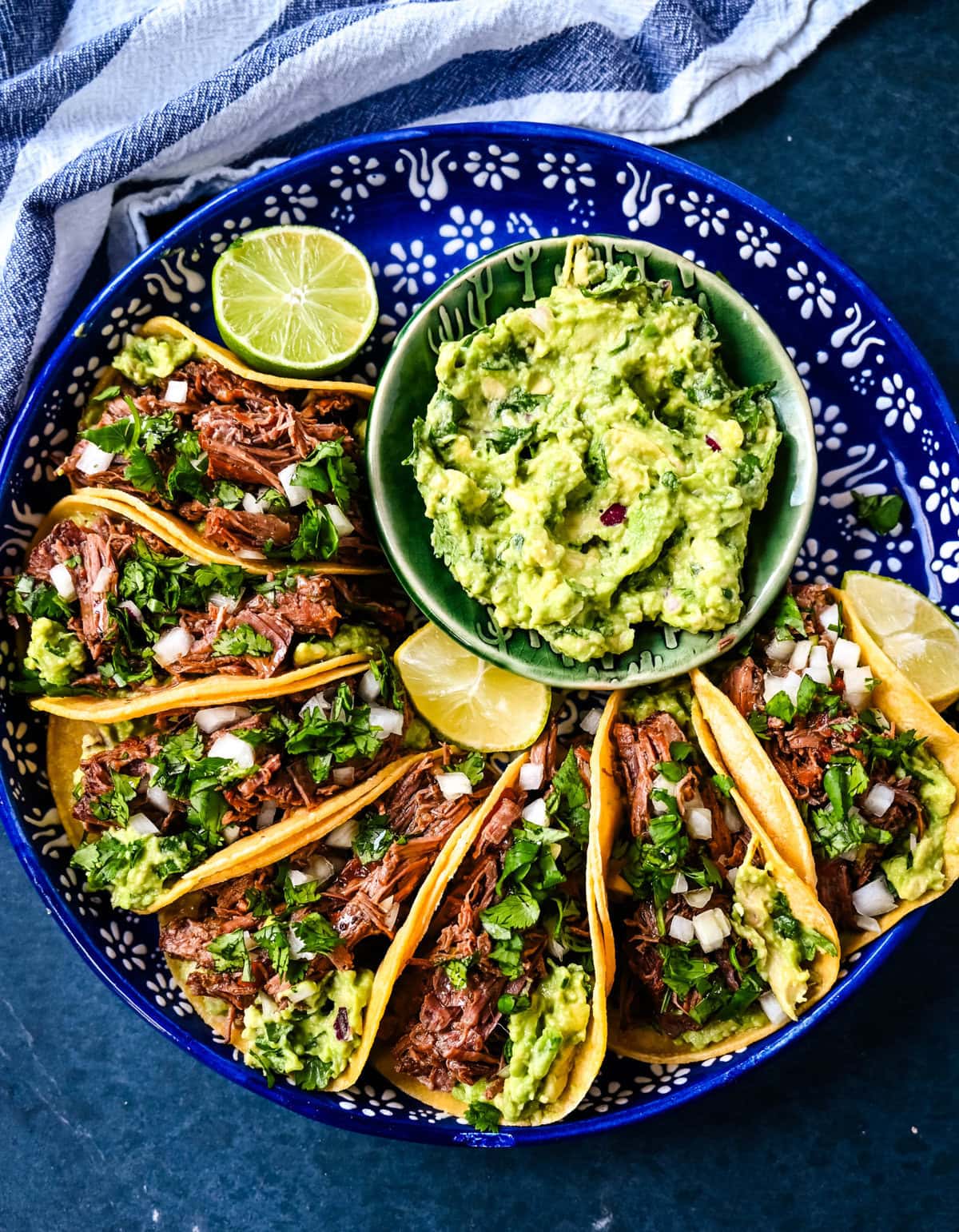 Tender, juicy, flavorful shredded beef with corn tortillas, fresh homemade guacamole, and a touch of cilantro and onion. These Slow Cooker Beef Tacos are so easy to make and everyone loves them!