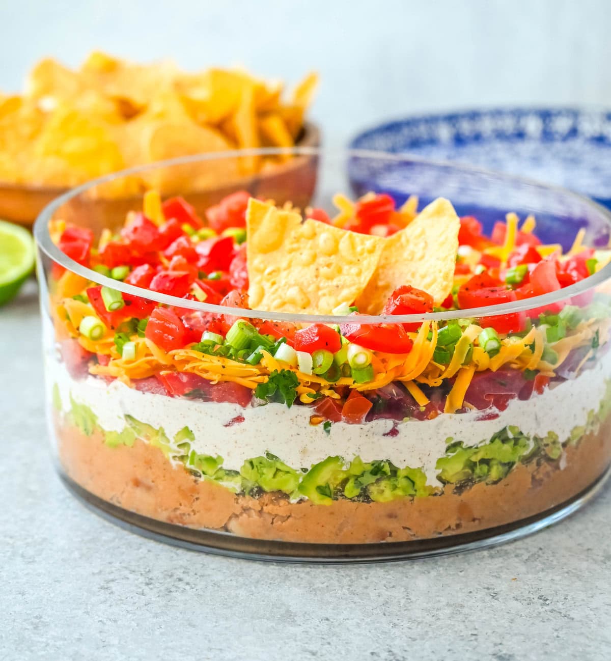 Seven-layer dip is a colorful, Tex-Mex-inspired appetizer featuring layers of refried beans, guacamole, seasoned sour cream, salsa, shredded cheese, fresh tomatoes, and sliced black olives. It’s popular because it’s easy to make, makes a stunning presentation, is delicious, and always a hit at parties or game-day gatherings. Whether you’re hosting a Super Bowl watch party or a casual family get-together, a classic 7 layer dip is guaranteed to impress.