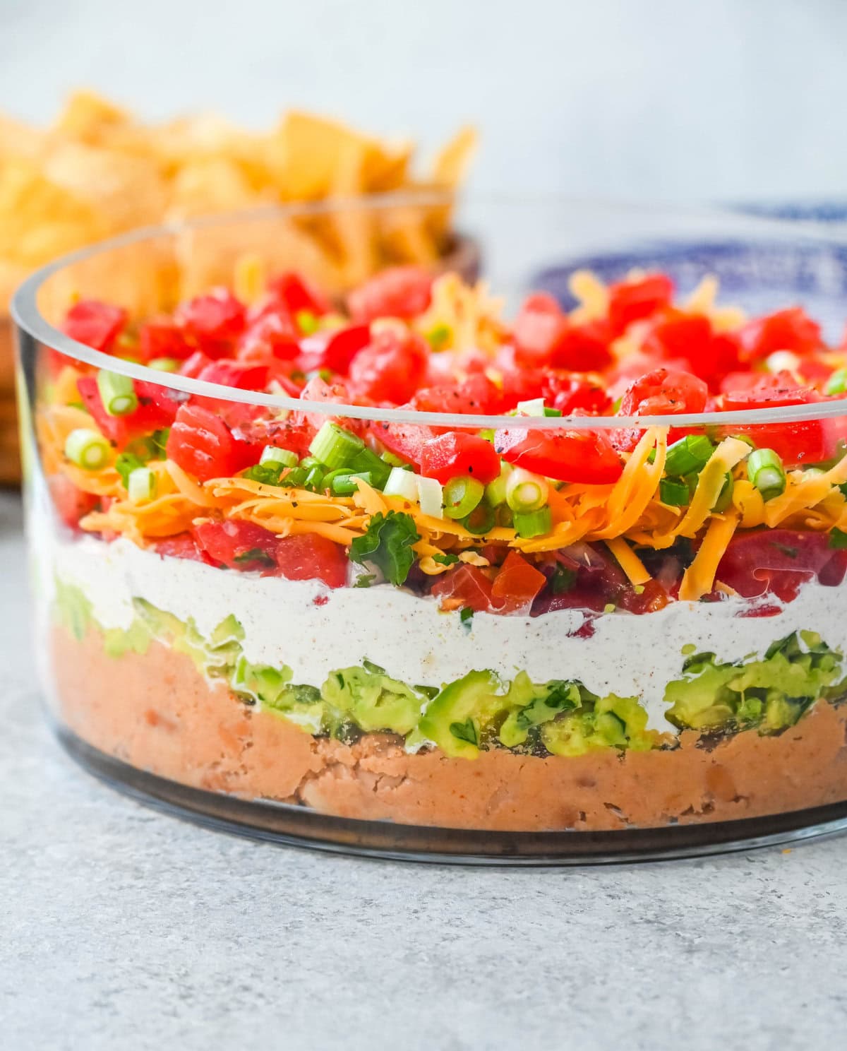 Seven-layer dip is a colorful, Tex-Mex-inspired appetizer featuring layers of refried beans, guacamole, seasoned sour cream, salsa, shredded cheese, fresh tomatoes, and sliced black olives. It’s popular because it’s easy to make, makes a stunning presentation, is delicious, and always a hit at parties or game-day gatherings. Whether you’re hosting a Super Bowl watch party or a casual family get-together, a classic 7 layer dip is guaranteed to impress.