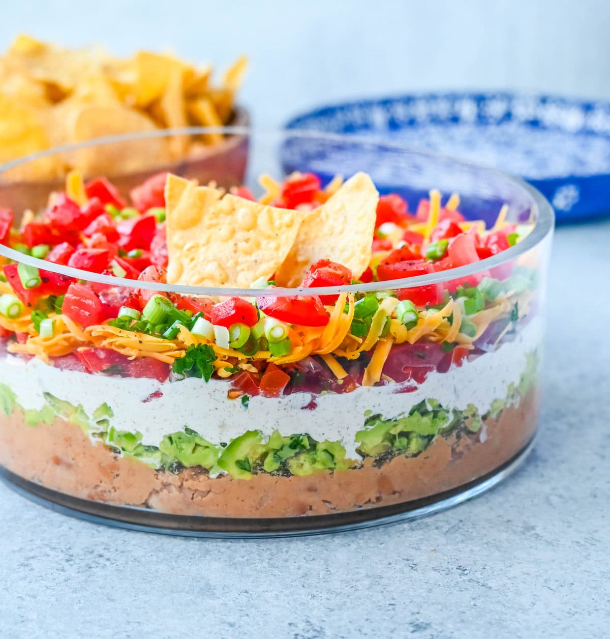 Seven-layer dip is a colorful, Tex-Mex-inspired appetizer featuring layers of refried beans, guacamole, seasoned sour cream, salsa, shredded cheese, fresh tomatoes, and sliced black olives. It’s popular because it’s easy to make, makes a stunning presentation, is delicious, and always a hit at parties or game-day gatherings. Whether you’re hosting a Super Bowl watch party or a casual family get-together, a classic 7 layer dip is guaranteed to impress.