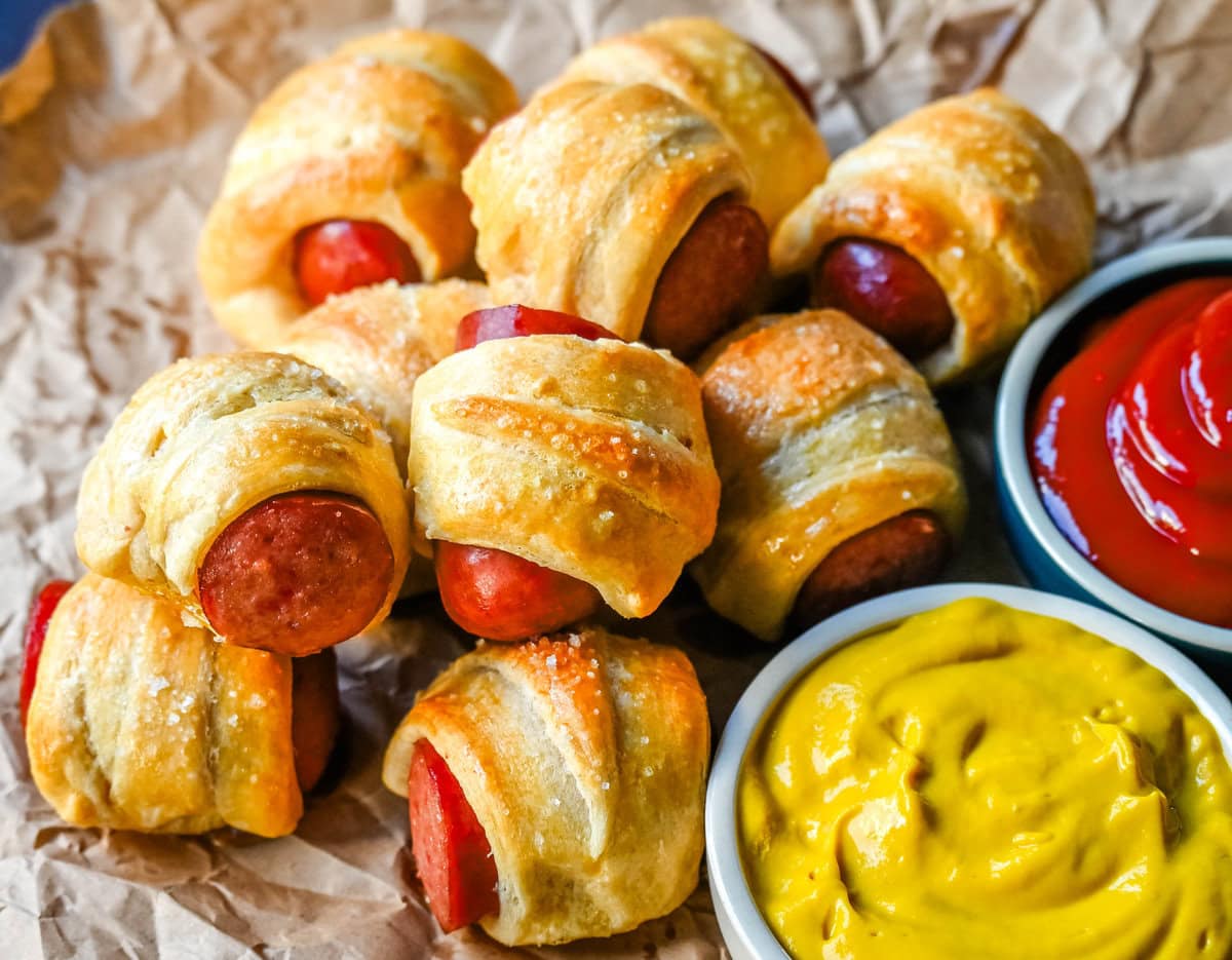 These Pigs in a Blanket are a classic, crowd-pleasing appetizer with juicy hot dogs wrapped in flaky crescent dough and baked until golden. These crescent roll hot dogs are so easy to prepare and you can even customize them into pretzel dogs. This is such an easy party appetizer to whip up in less than 30 minutes.