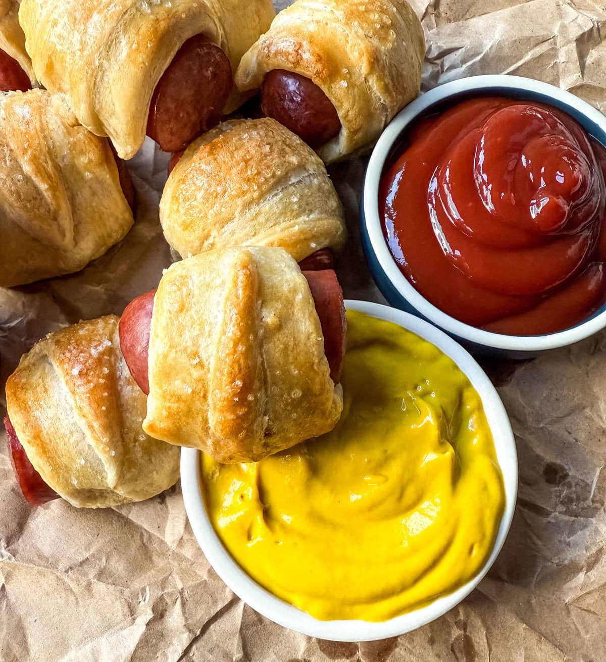 These Pigs in a Blanket are a classic, crowd-pleasing appetizer with juicy hot dogs wrapped in flaky crescent dough and baked until golden. These crescent roll hot dogs are so easy to prepare and you can even customize them into pretzel dogs. This is such an easy party appetizer to whip up in less than 30 minutes.