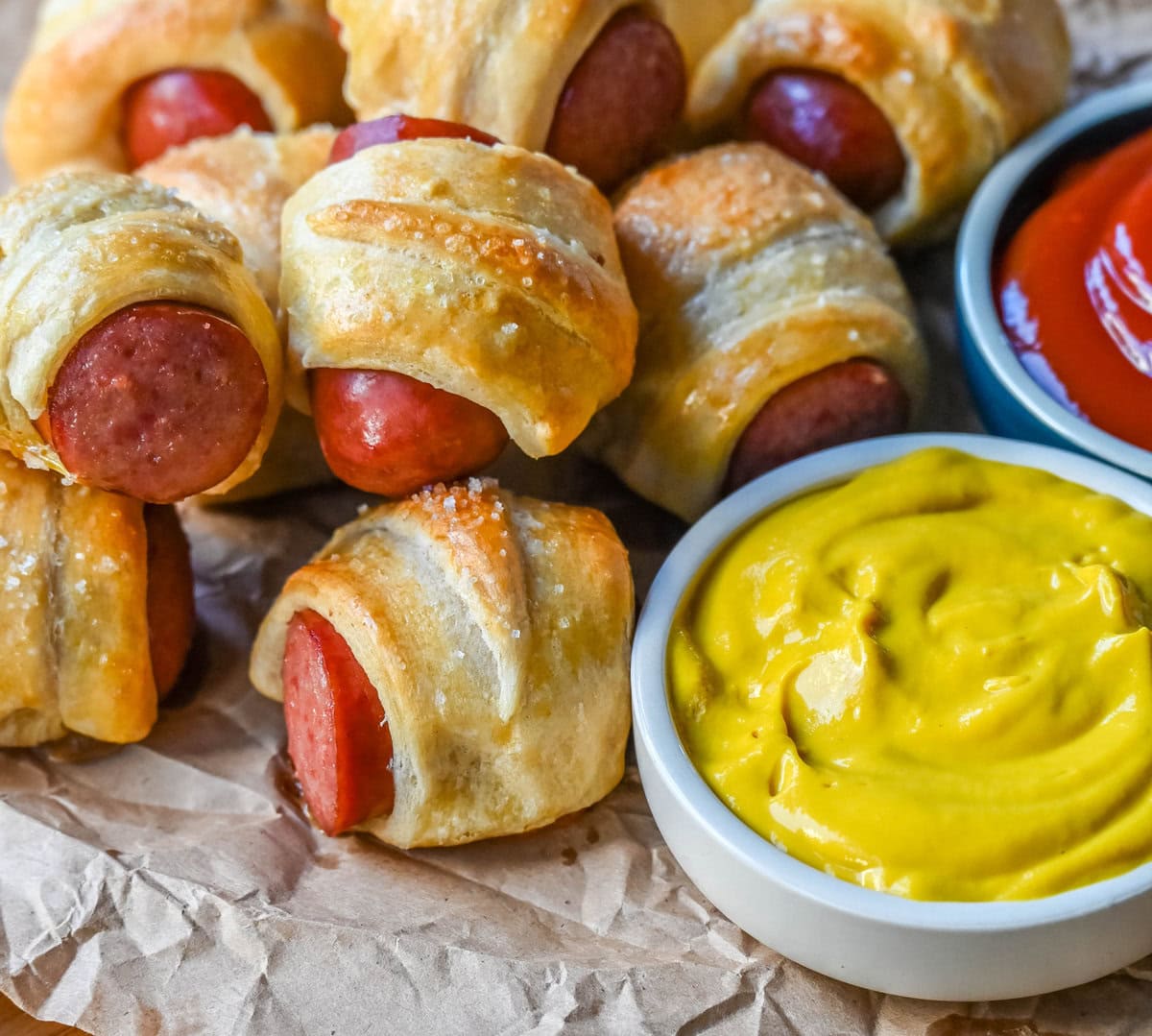 These Pigs in a Blanket are a classic, crowd-pleasing appetizer with juicy hot dogs wrapped in flaky crescent dough and baked until golden. These crescent roll hot dogs are so easy to prepare and you can even customize them into pretzel dogs. This is such an easy party appetizer to whip up in less than 30 minutes.