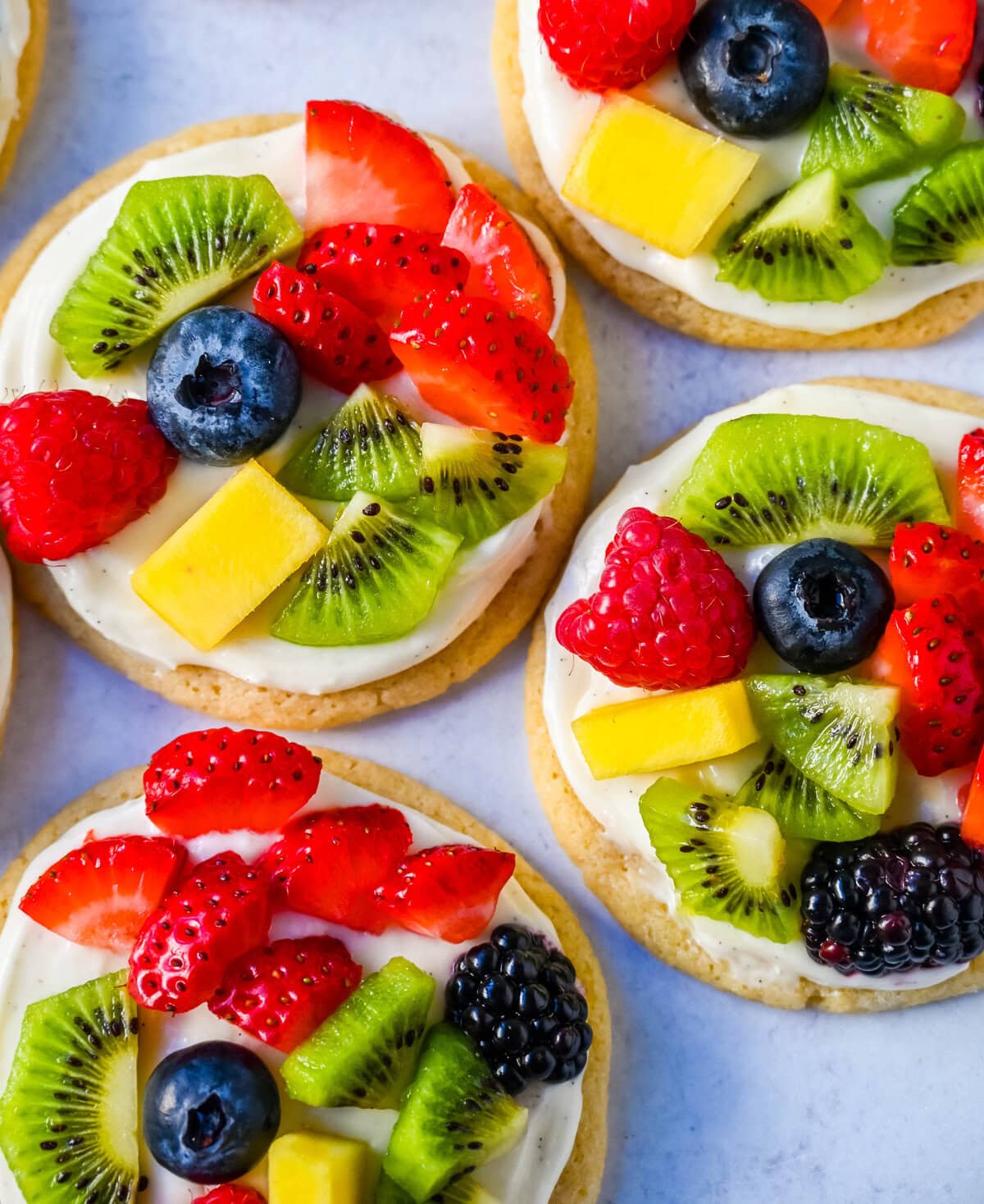 These Fruit Pizza Cookies are made with soft, chewy, buttery sugar cookies topped with a sweet cream cheese frosting and fresh fruit. These Sugar Cookie Fruit Pizzas are always a huge hit!