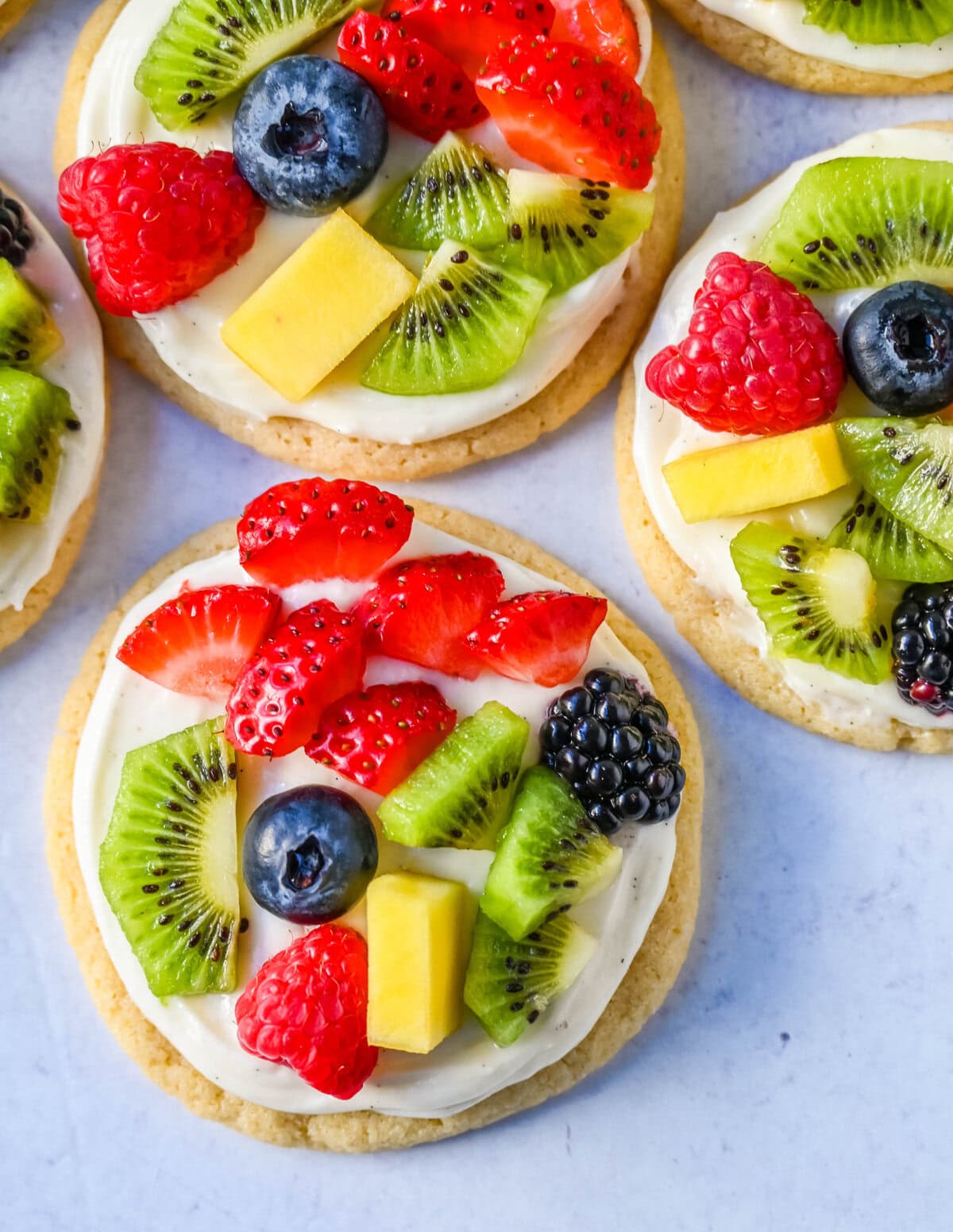 These Fruit Pizza Cookies are made with soft, chewy, buttery sugar cookies topped with a sweet cream cheese frosting and fresh fruit. These Sugar Cookie Fruit Pizzas are always a huge hit!