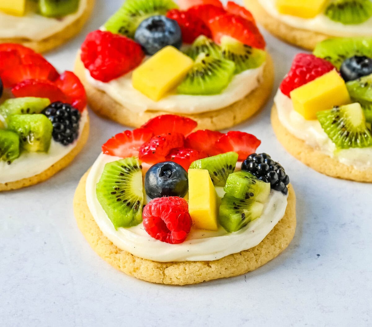 These Fruit Pizza Cookies are made with soft, chewy, buttery sugar cookies topped with a sweet cream cheese frosting and fresh fruit. These Sugar Cookie Fruit Pizzas are always a huge hit!